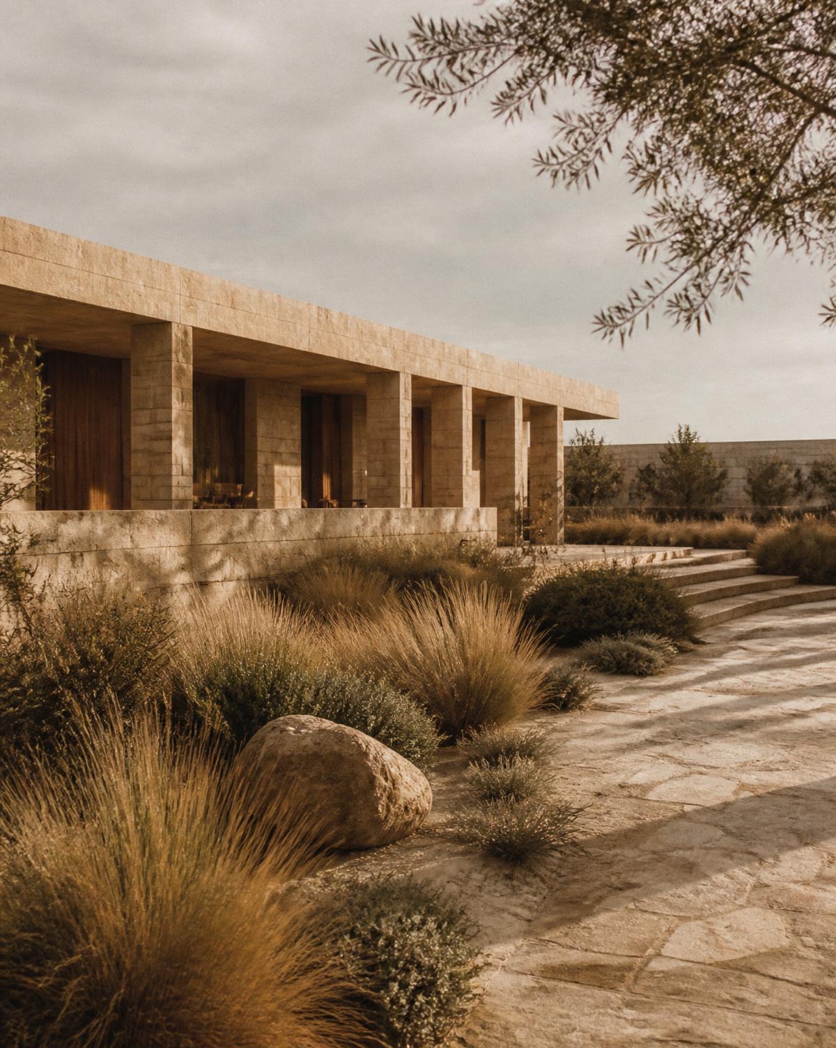 Low limestone pavilion set into a dry garden with long afternoon shadows